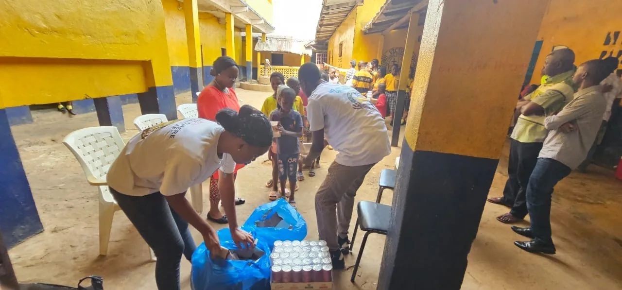Volunteers handing out bags of supplies and bottled water in the orphanage courtyard