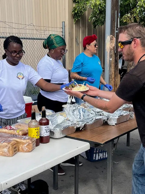 Volunteers serving plates of hot food from the outreach tables