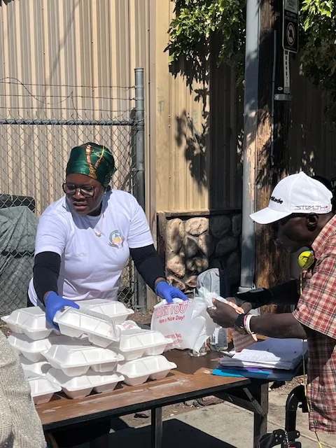 A volunteer handing a packed meal across the table to a neighbor