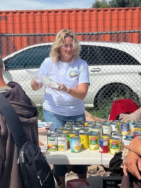 A volunteer in a Kyne Hands Foundation shirt serving at the outreach table