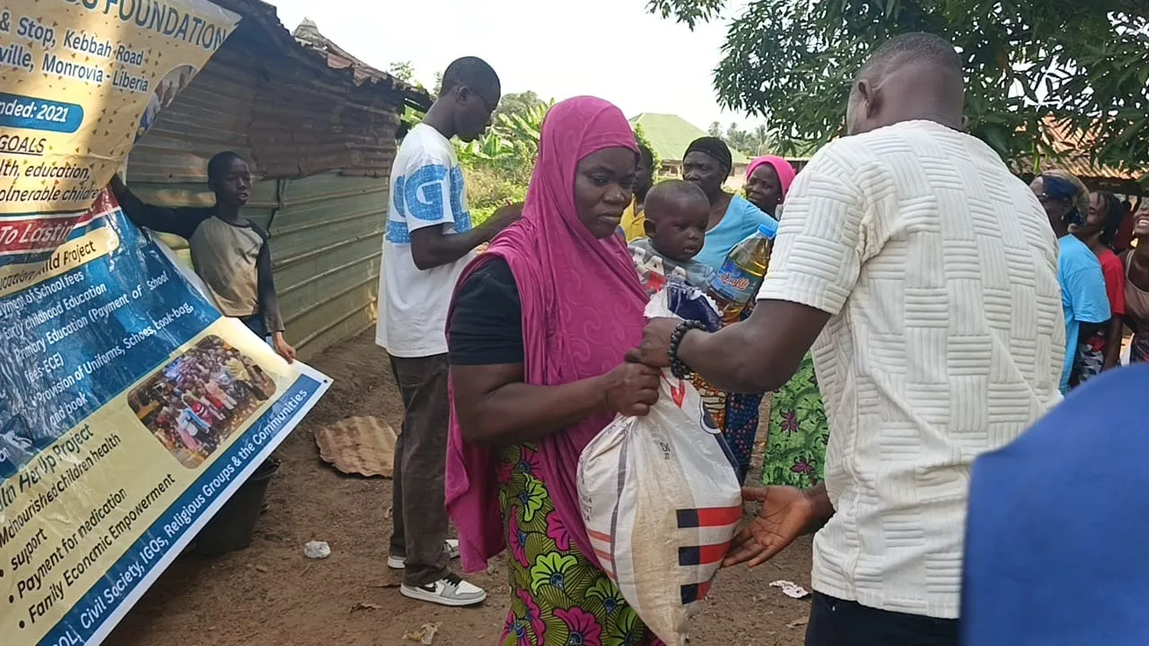 A bag of rice handed to a mother holding her baby at a Kyne Hands Foundation distribution in Liberia