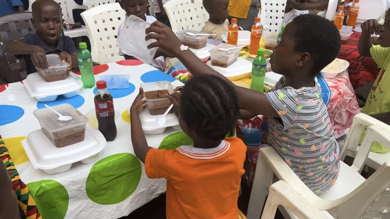 Children eating lunch together at a long table in Liberia