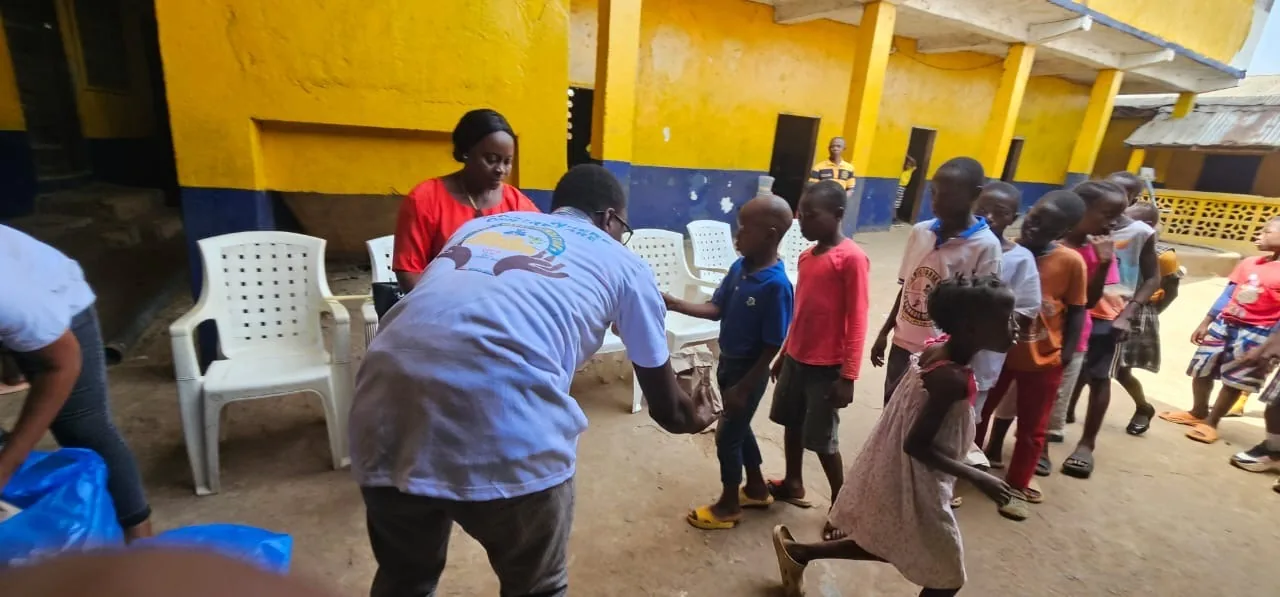 A volunteer handing out gifts to children in the orphanage courtyard