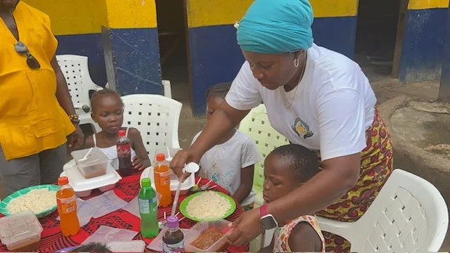 Cynthia serving a meal to young children at a table in Liberia